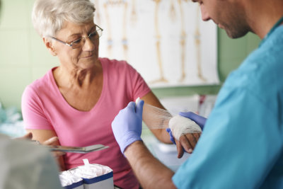 caregiver attending senior patient's wound