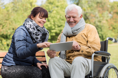 disabled man and caregiver with a tablet